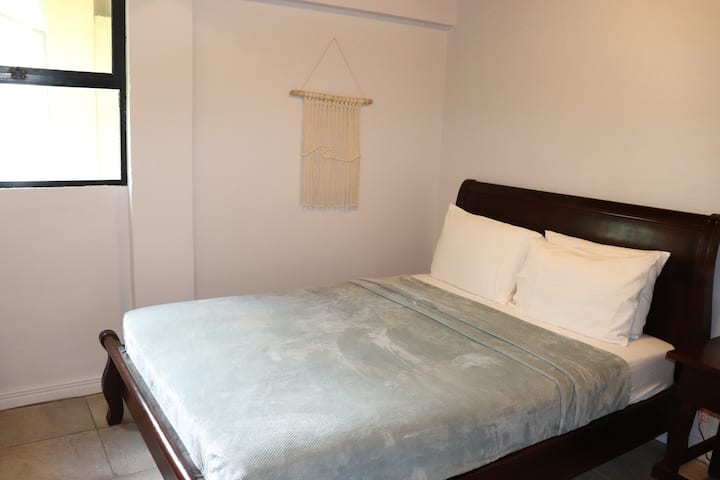 La habitación cuenta con una cama tamaño queen, aire acondicionado y techos de madera abovedados.