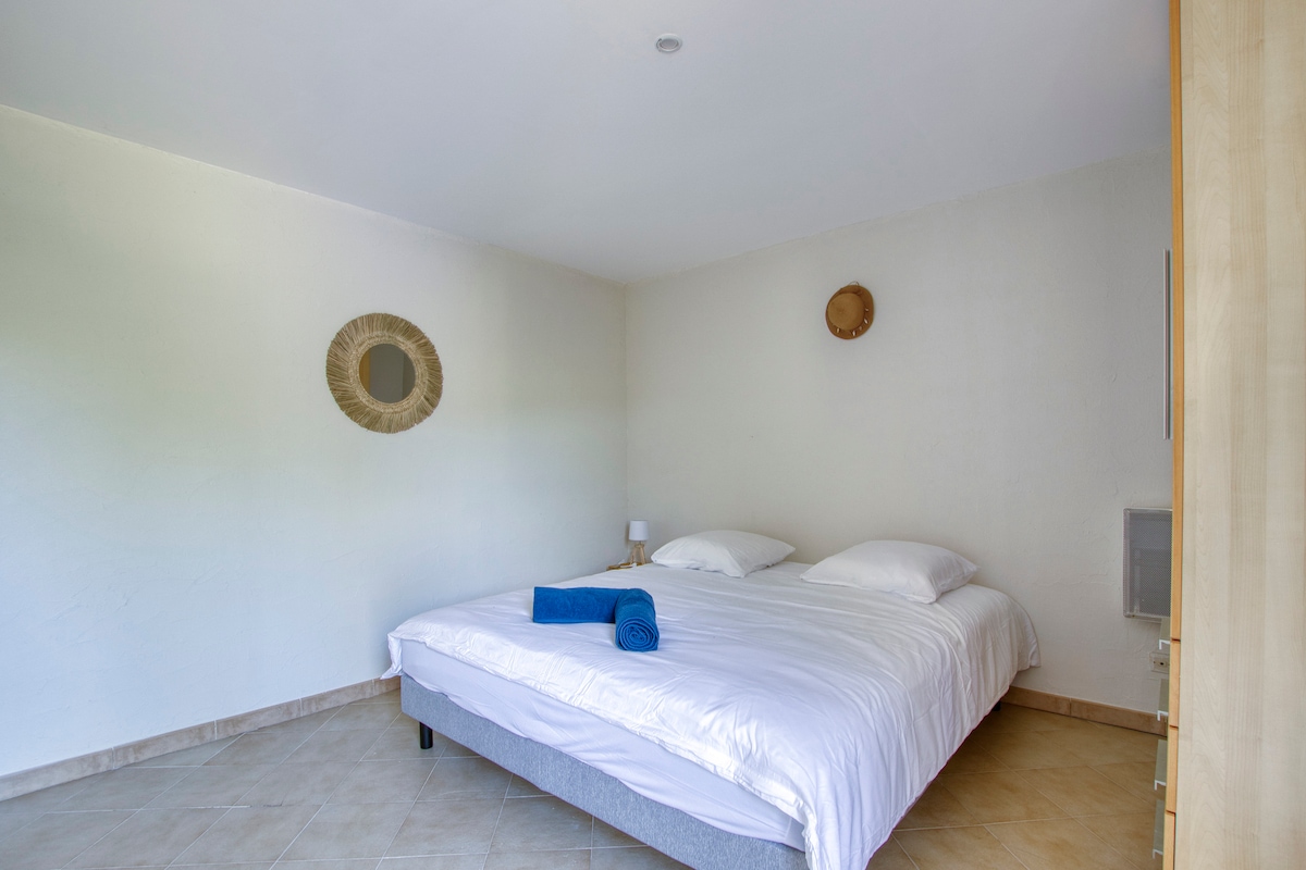 غرفة نوم رئيسية بسرير بحجم كينج مع غرفة استحمام، وإمكانية الوصول إلى الهواء الطلق للخصوصية، وكرسي واحد، ومبرد، وكرسي مرتفع للأطفال، ومنضدتين ليليتين ومصباحين، ومصراع واحد (صورة يونيو 2023)