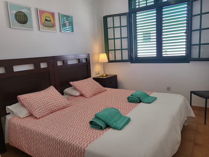 Two-bed room with a ceiling fan.