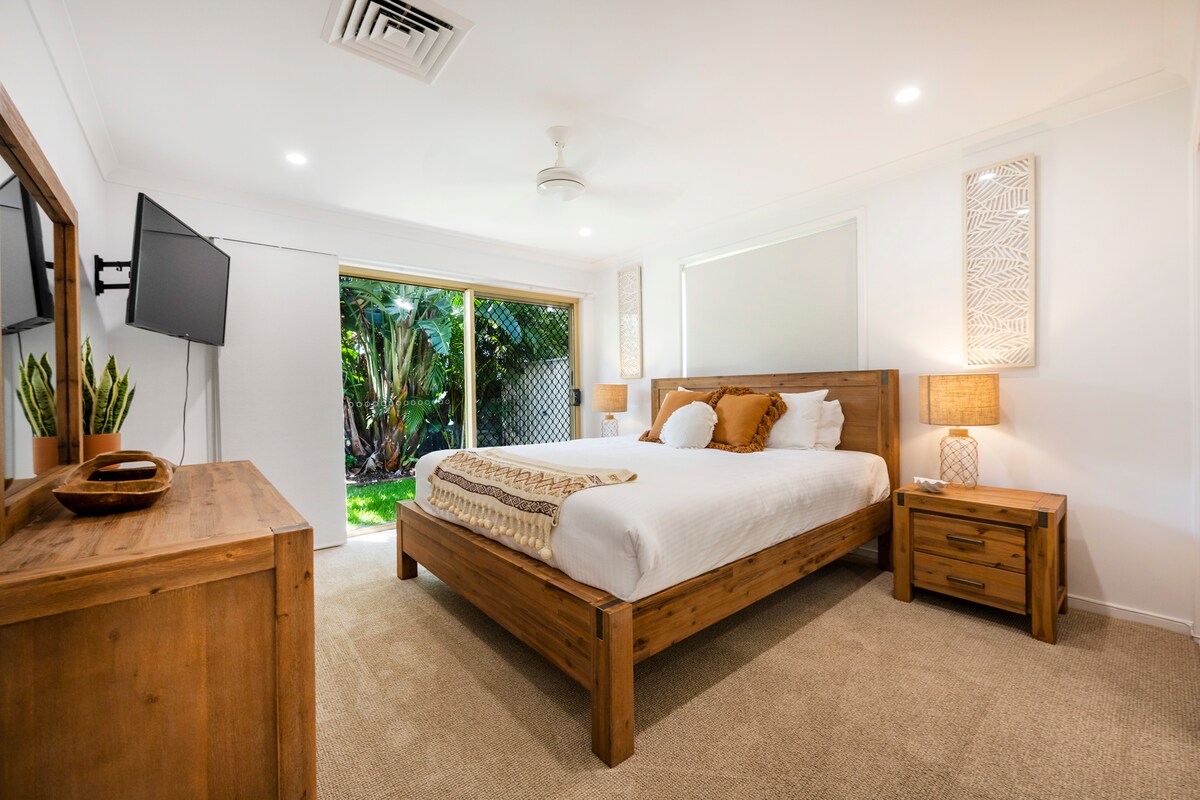 Dormitorio principal con cama tamaño queen, televisión, bata incorporada y acceso al patio trasero.