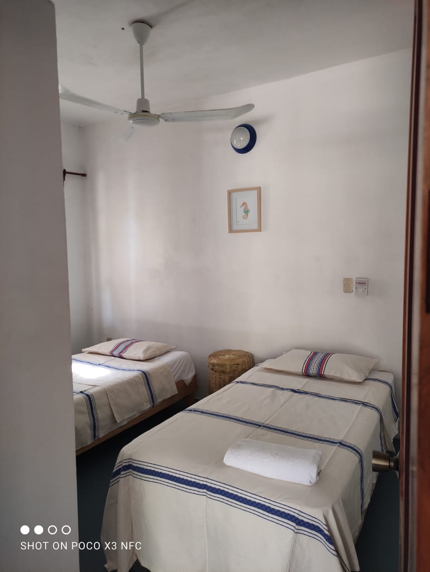 חדר שינה עם שתי מיטות יחיד, מאוורר, מתלה בגדים