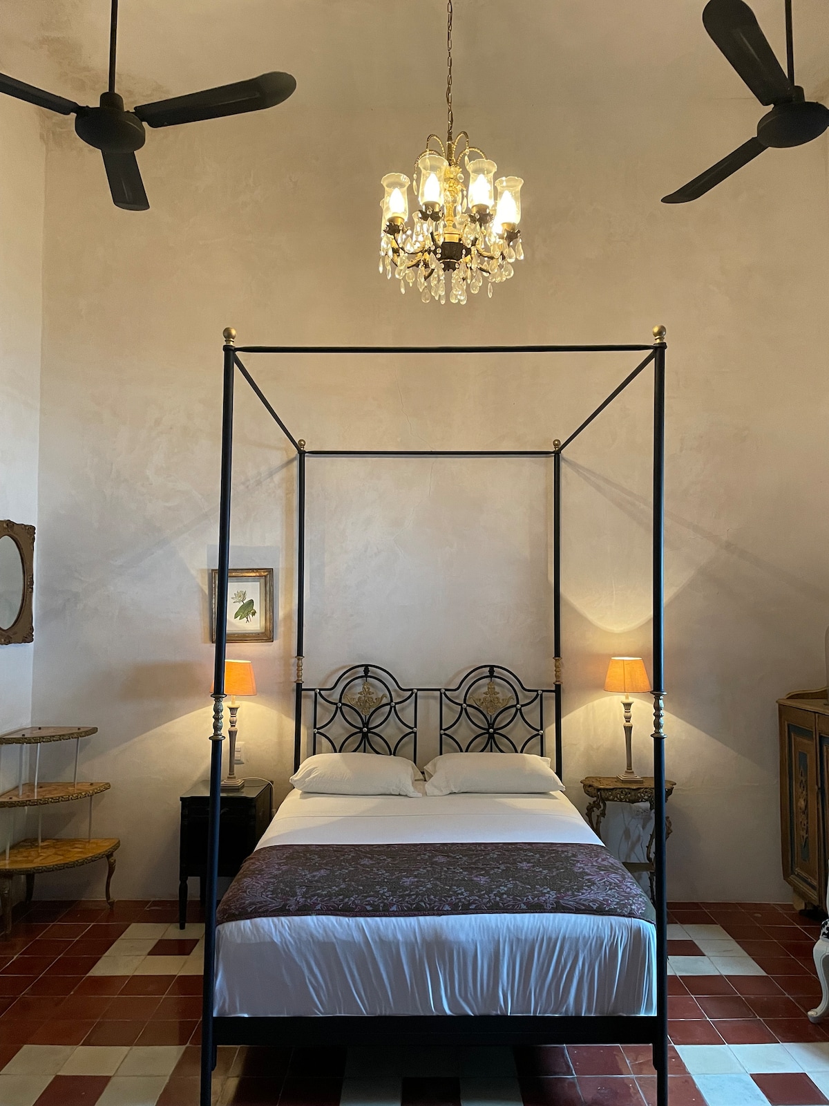 Spavaća soba s bračnim krevetom, starim lusterom,  2 ventilatora i klima-uređajem.