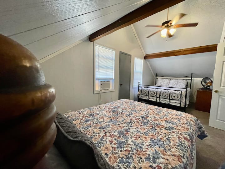 二楼后方的次卧室配有两张标准双人床。还有一个全尺寸梳妆台，方便您使用。 灰色的门通往步出式阳台，可欣赏森林美景。