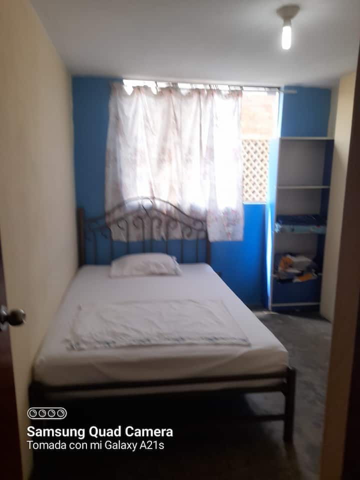 Quarto com cama de casal com janela em direção à rua