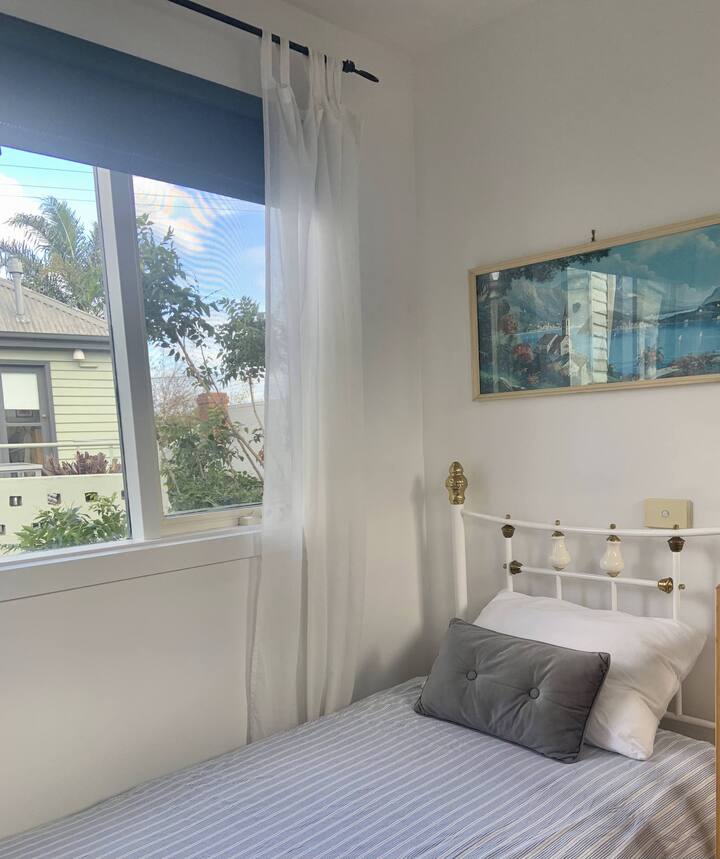 pequeño dormitorio en la planta superior con cama individual y mesita de noche, lámpara y perchero