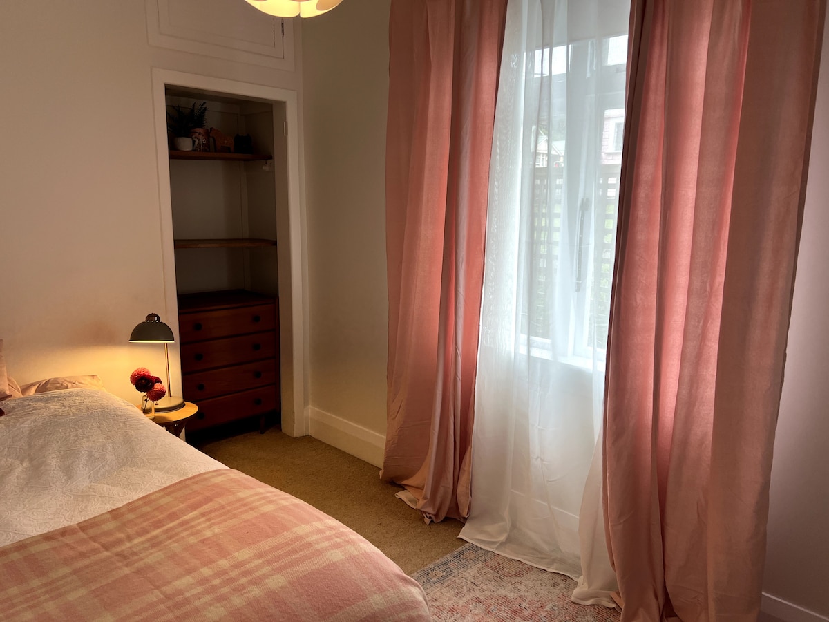 ห้องสีชมพู เตียงคิงไซส์เดี่ยวและโต๊ะเล็กๆ และลิ้นชักสำหรับเก็บเสื้อผ้า พื้นที่เงียบสงบ