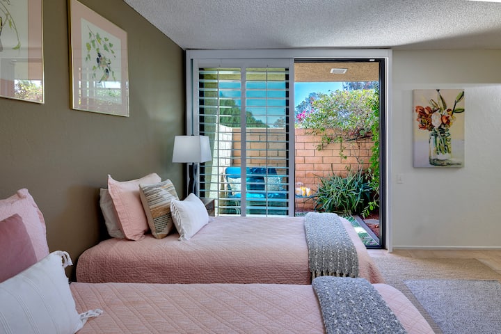 חדר שינה לאורחים עם שני רווקים או מיטת קינג סייז שהוסבה עם חלונות סגורים שנפתחים לפטיו גינה פרטי, ארון מראות, שולחן כתיבה וכיסא, טלוויזיה עם רוקו, צמוד עם ריהוט, שירותים ומקלחת סגורה מזכוכית.