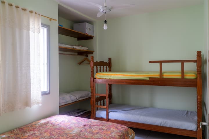 Quarto com cama de casal, beliche, teto fan and charcuterie.