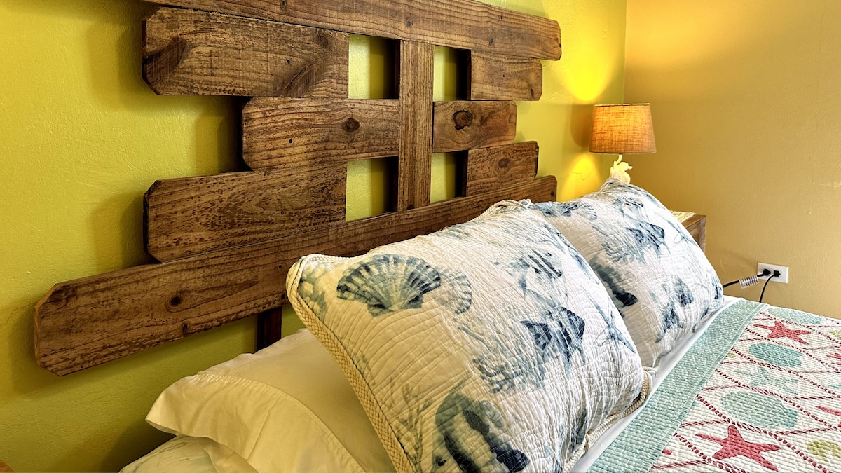 The master bedroom has a comfy queen sized bed with a garden view through the window.