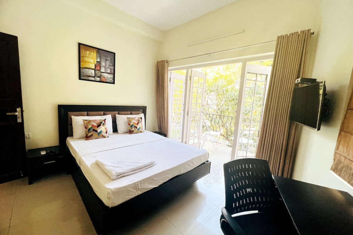 Tu dormitorio privado con balcón adjunto, cama extra larga de diseño, TV de pantalla plana, silla de salón y baño adjunto.