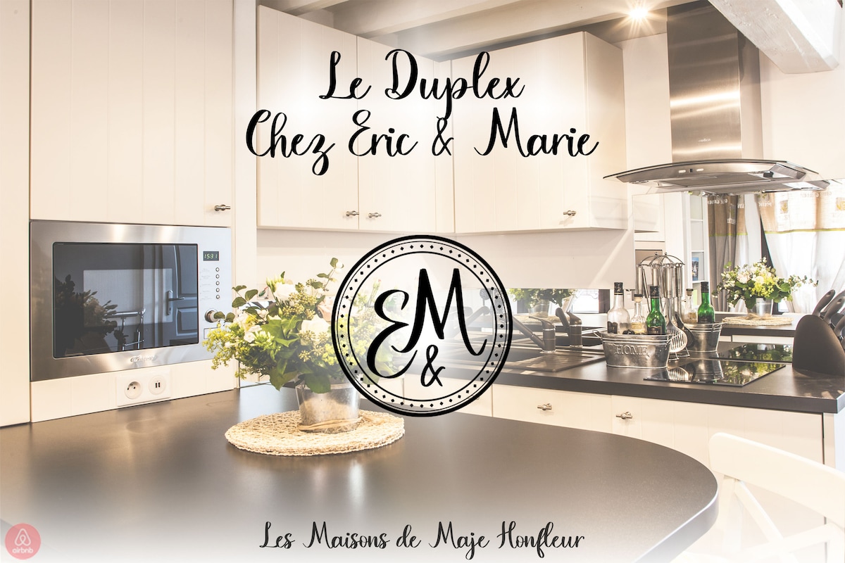 The kitchen area is characterized by modern appliances and sleek cabinetry, featuring a central island that invites meal preparation. A vase of fresh flowers adds a touch of elegance, while the overall layout promotes a warm and functional cooking space.