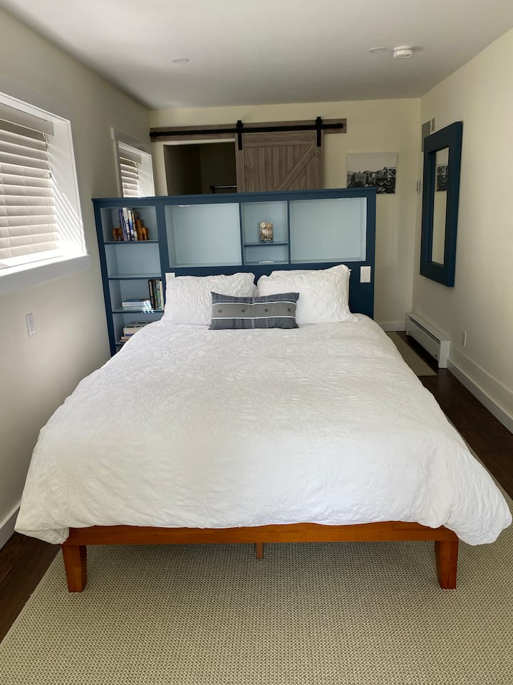 Спална соба со брачен кревет со сопствена табла за глава со вградени светла за читање.