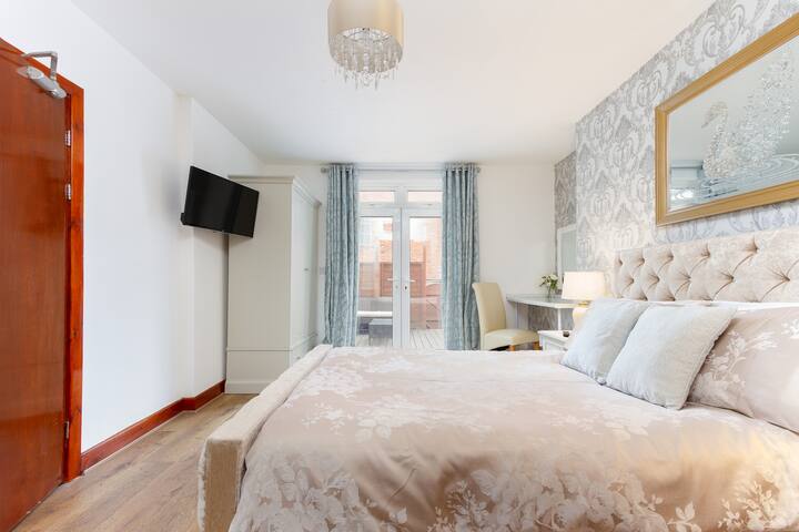 Dhoma kryesore e gjumit e apartamentit nr. 7
Krevati dopio, komodinat pranë krevatit, abazhurët pranë krevatit, tavolina e tualetit, televizori inteligjent i montuar në mur.  Dush, tualet dhe lavaman në banjë. Dyer franceze që të çojnë në një zonë private me dysheme druri.