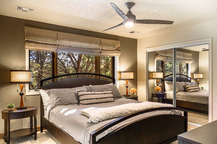 加大双人床卧室，配有舒适的床上用品、充足的橱柜空间和树木繁茂的景观。