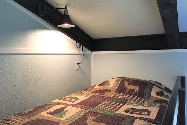 Elevated Top Bunk with Twin XL mattress. Along the wall is a shelf for extra storage. Not suitable for kids under 5.