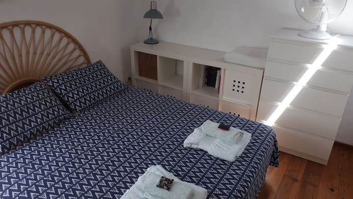 Dhomë gjumi me një krevat dopio "queen" në mes të dhomës, e arritur nga një shkallë "pak e pjerrët"  