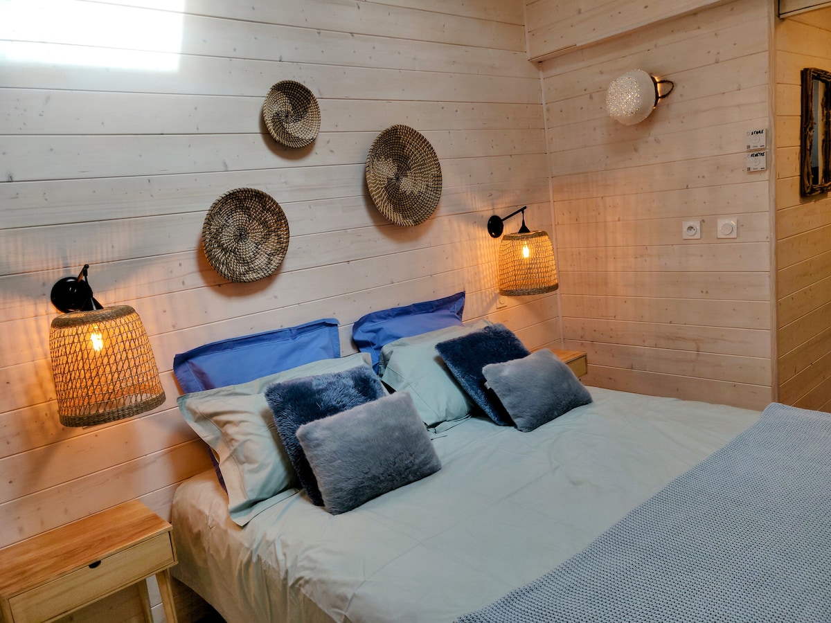 A well-appointed sleeping area features a spacious bed with soft bedding in calming hues. Decorative woven wall art is arranged above the bed, while two bedside lamps provide warm lighting on either side. Light streams through a window, enhancing the tranquil atmosphere.