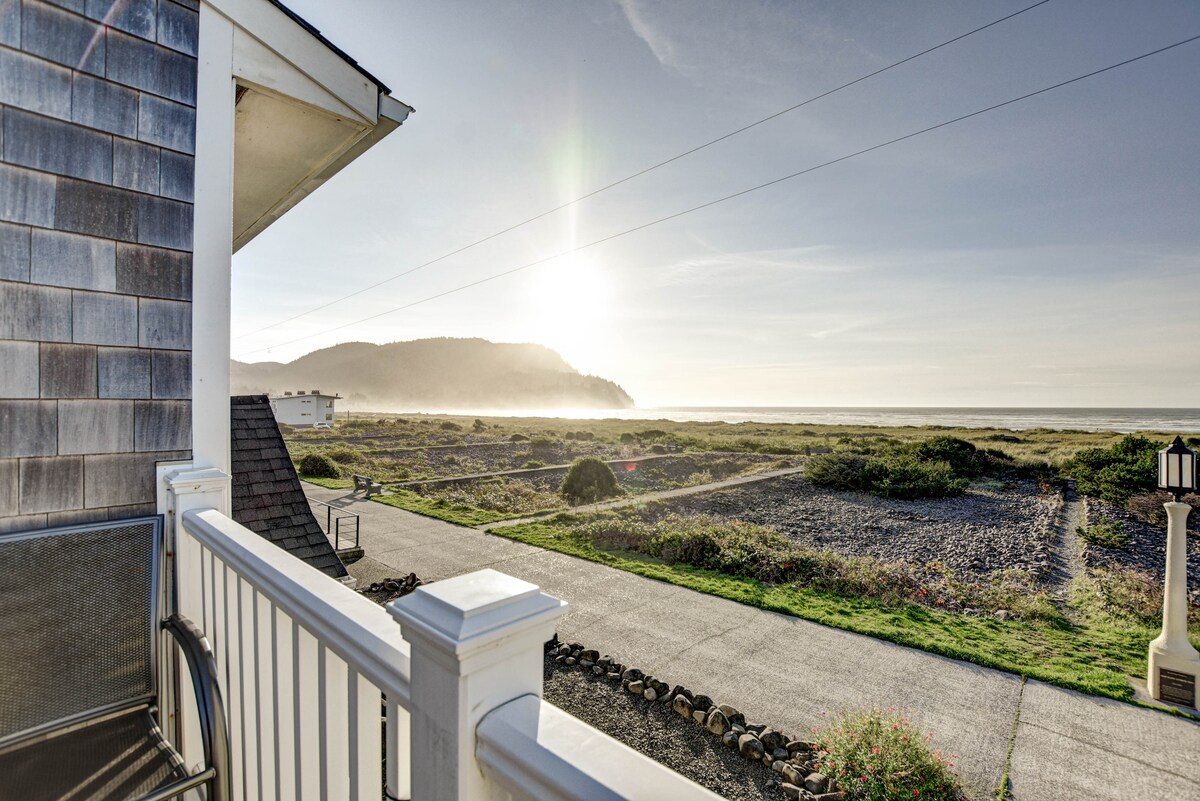A view from the private oceanfront deck captures the horizon where the sun rises over a serene beach landscape. The foreground features a gravel path lined with coastal vegetation, leading toward distant hills under a clear sky.