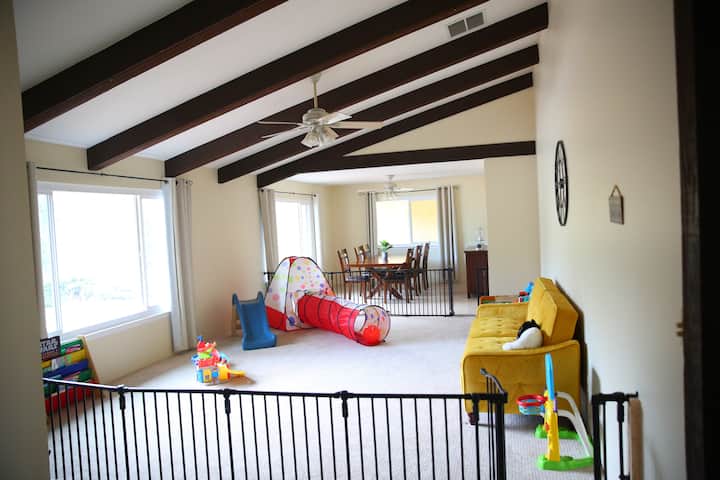 Amplia zona de juegos vallada con toneladas de juguetes y libros, segura y divertida para niños pequeños.