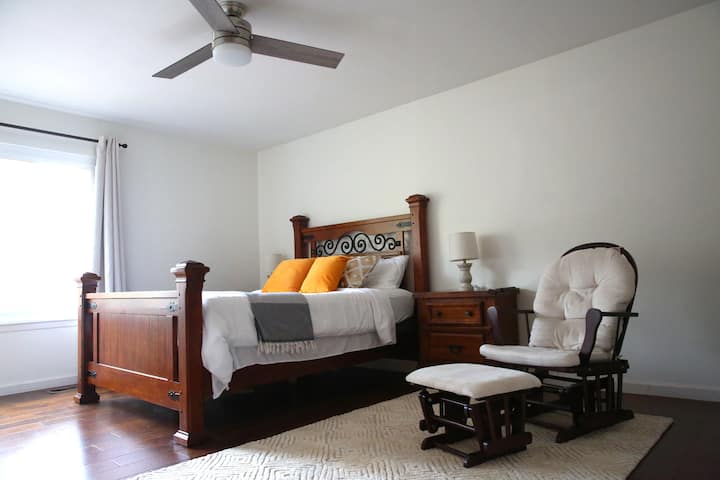 Dormitorio n .º 4 con cama tamaño queen, cuna de tamaño completo, cambiador, silla de enfermería y espacio de oficina.