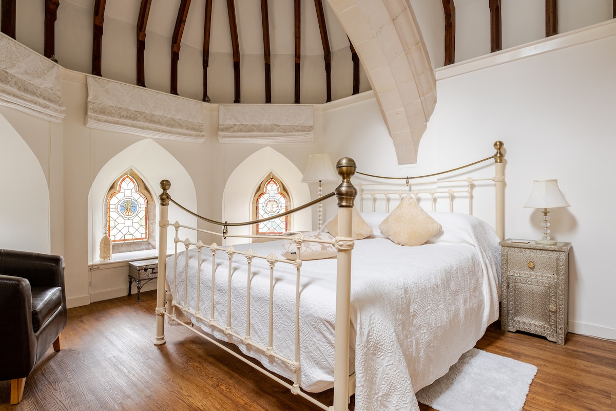 Je rustige plek onder het originele kapelplafond van The Scriptorium Retreat, omringd door prachtige glas-in-loodramen