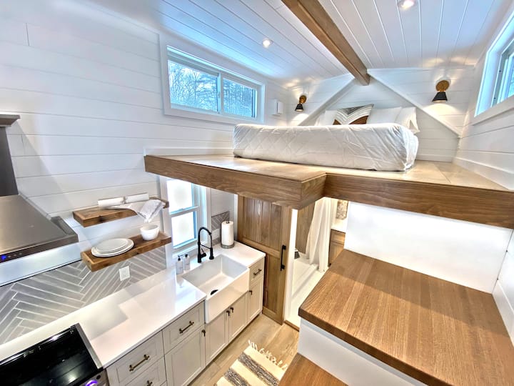 The sleeping loft is surprisingly roomy for a tiny home, with dual dormers, sliding windows for plenty of light, LED recessed lighting plus individual reading lights, and outlets. Comfy queen-size memory foam mattress with 100% cotton sheets.