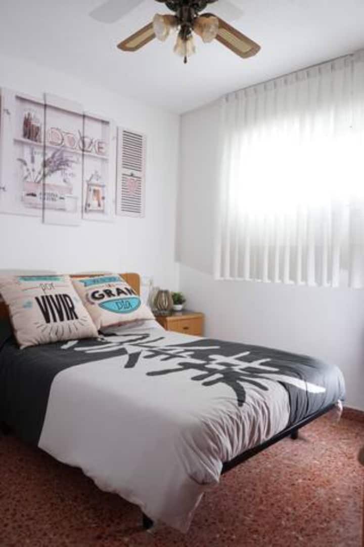 Спална соба со двоен кревет и вентилатор на таванот. Паметен телевизор.