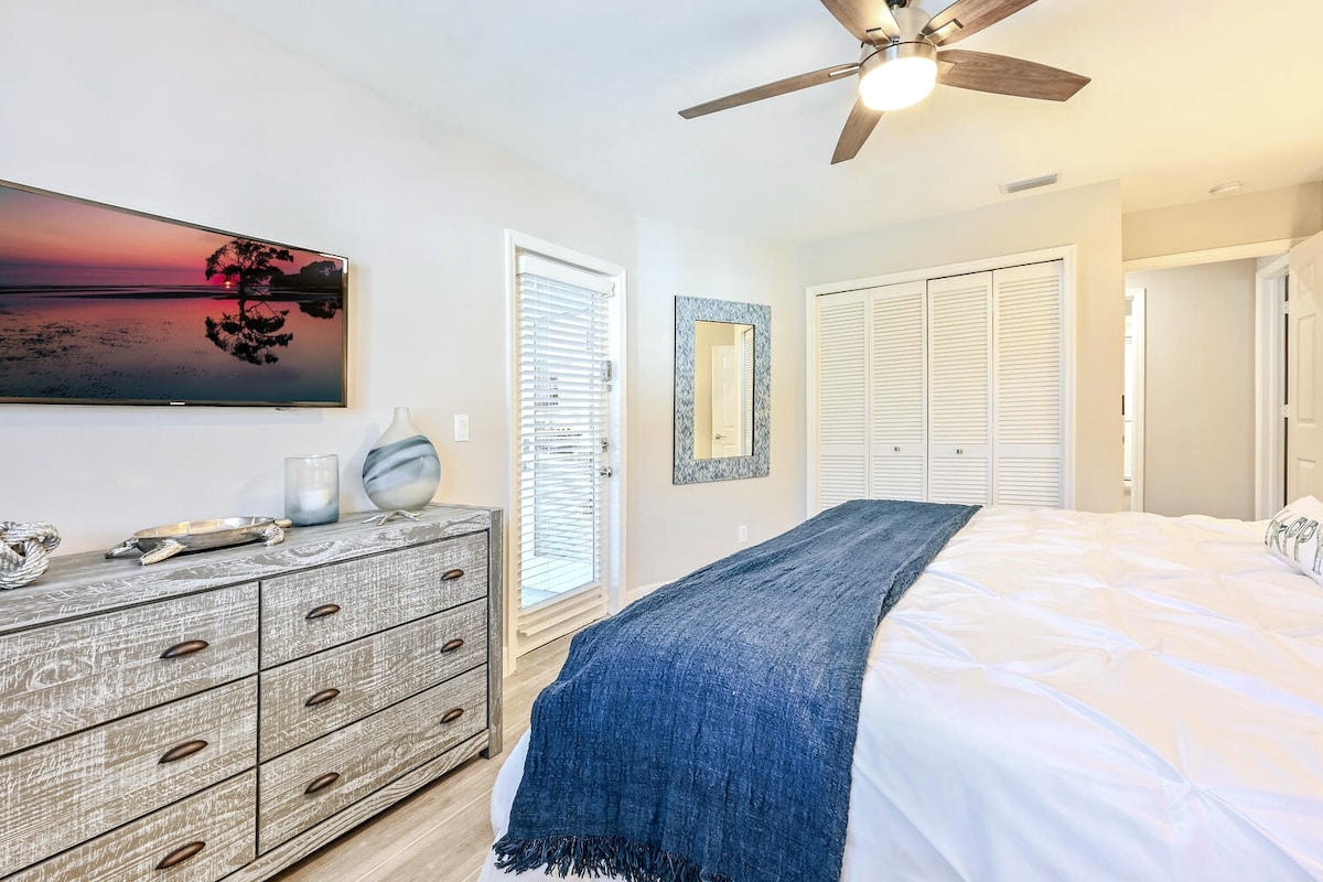 Master bedroom with king size bed and access door to lanai. W/ a large smart TV wall mounted. 