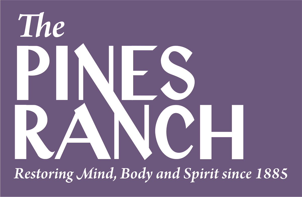 The logo of The Pines Ranch is displayed prominently, featuring bold white lettering against a rich purple background. The phrase 'Restoring Mind, Body and Spirit since 1885' is included, highlighting the Ranch's long-standing commitment to wellness and relaxation.