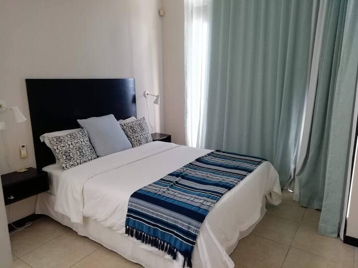 Dormitorio de invitados que conduce al balcón principal a través de puertas de vidrio apilables, tiene baño privado con ducha interior y exterior, cama doble y una litera, aire acondicionado nuevo y una televisión inteligente.