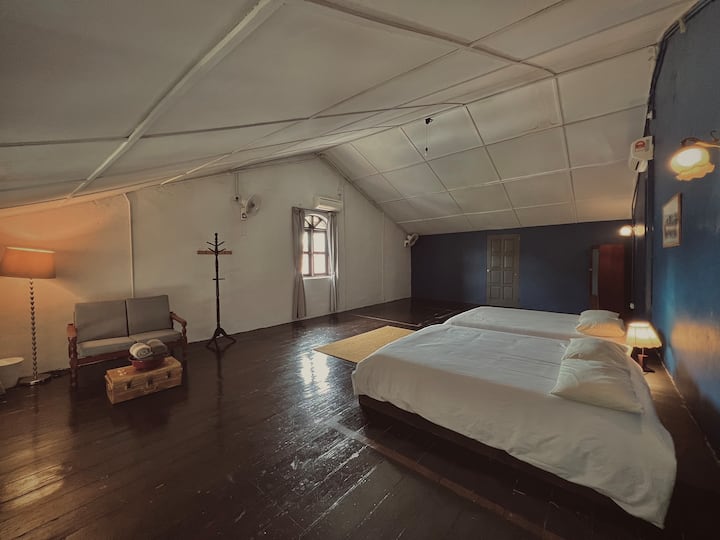 Loft Bedroom - Up in the loft, this wide, light-filled bedroom offers two beds, a cosy nook, and the peaceful charm of a heritage attic.