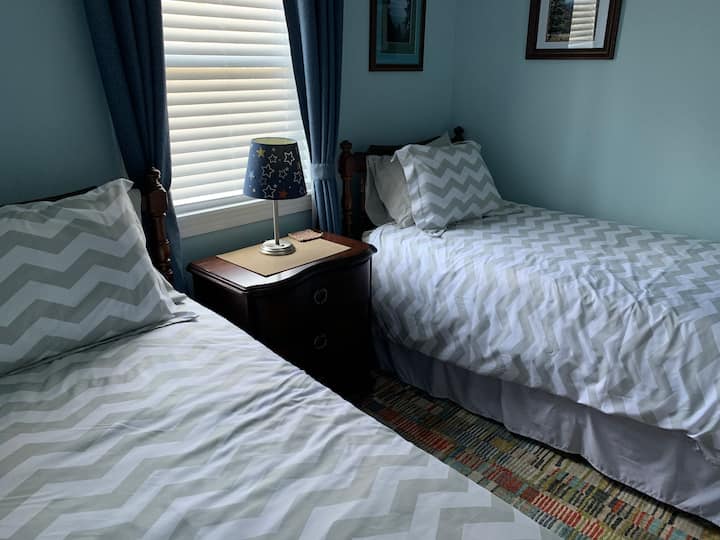 El segundo dormitorio tiene dos camas individuales.  También tenemos dos juegos disponibles.  Una de ellas incluye el cambiador de un bebé.  Puertos USB en un enchufe de pared detrás de una mesa de noche de 3 cajones.  