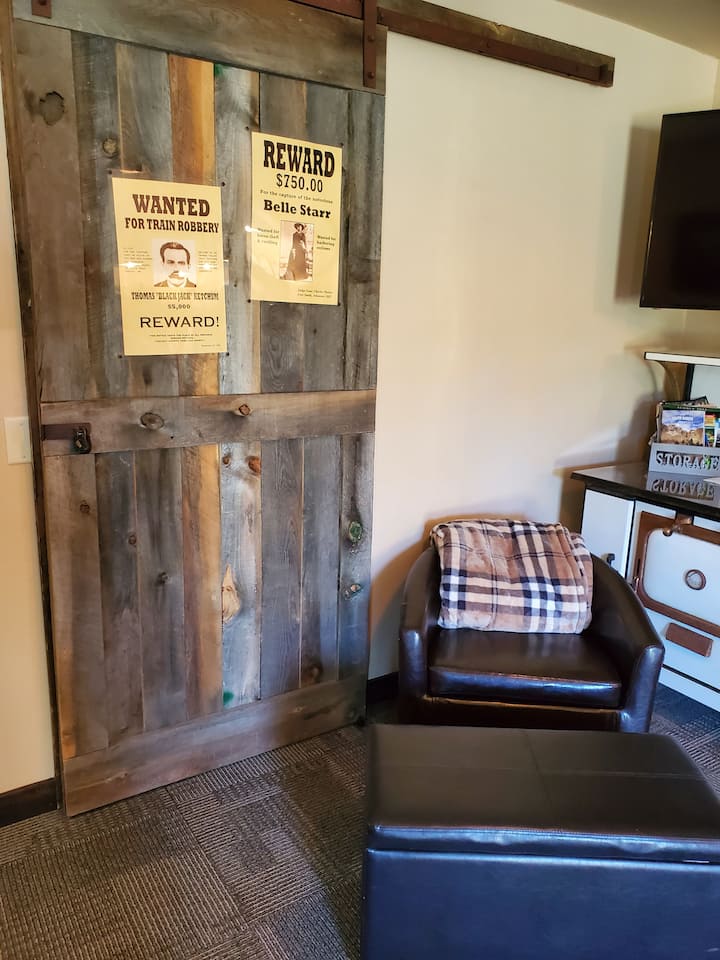 Zona de estar con sábanas de sofá cama en el taburete.