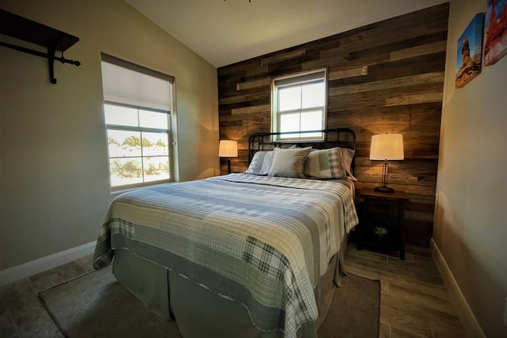 A barnwood wall adds rustic charm to this bedroom that includes a queen-sized bed. 