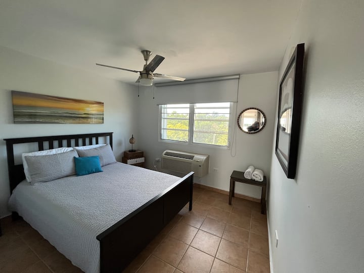 Dhoma e gjumit me pamje nga ana e pasme e rripit të gjelbër. Përmban dollap me pasqyrë të plotë, ajër të kondicionuar dhe ventilator tavani