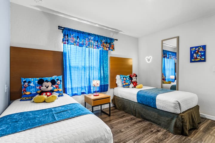 Habitación para niños temática de Disney Mickey & Friends en el segundo piso con 2 camas individuales, TV, cómoda, armario, etc., ofrece un espacio divertido para tus niños.