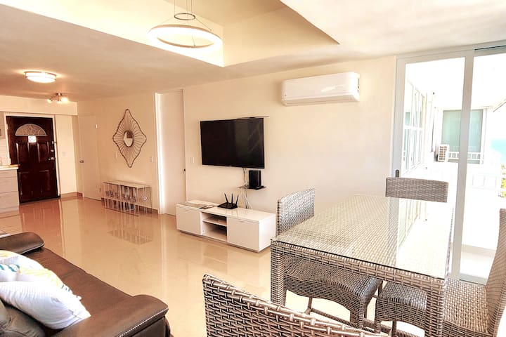 غرفة معيشة حديثة وواسعة بإطلالة على المحيط وتلفزيون ذكي ومكيف هواء.