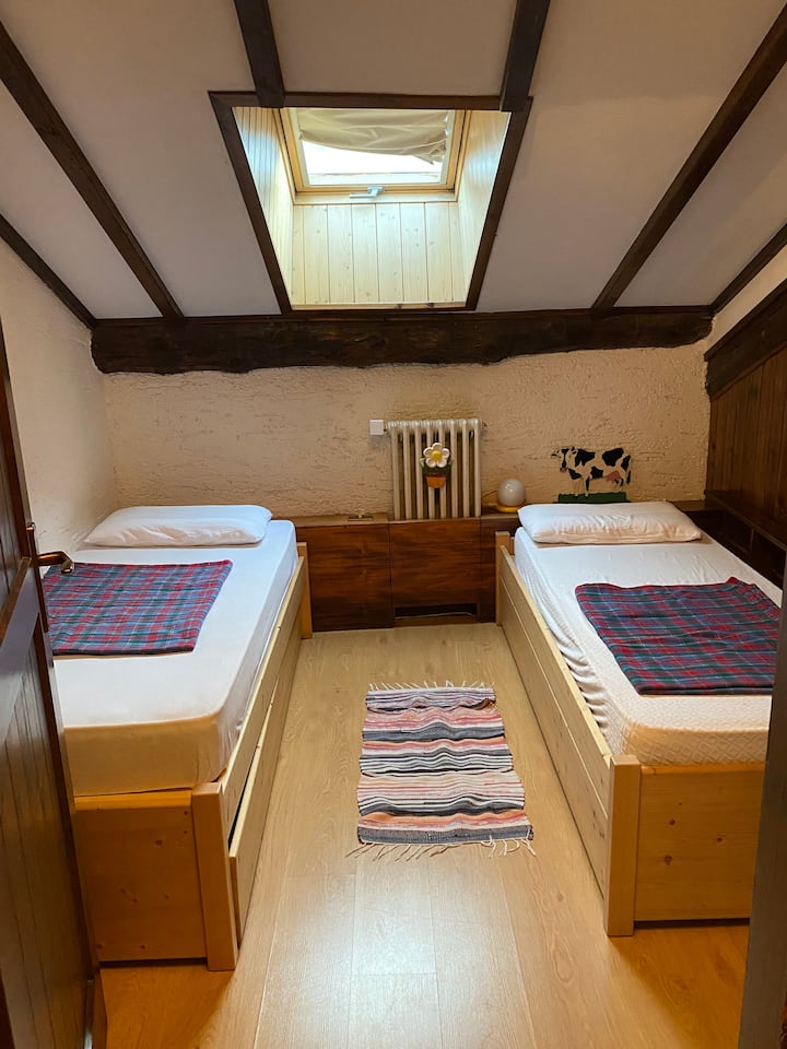 Dhoma e parë e gjumit në papafingo me dy krevate (plus një e tretë e lëvizshme). gardërobë dhe tavolinë pune