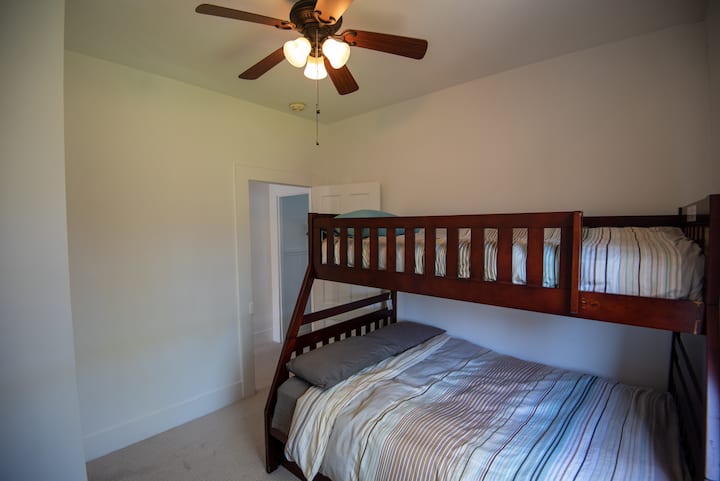 Dormitorio de literas con cama individual sobre cama doble extraíble y ventilador de techo