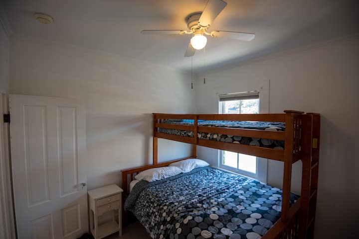 Dormitorio de California con cama individual sobre litera tamaño queen, ventilador de techo y armario grande.