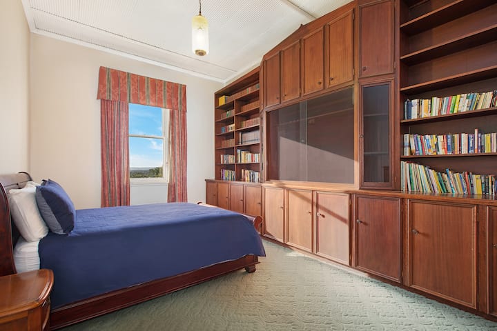 Bedroom with a queen sized bed in the library room sitauted on the raised ground floor.