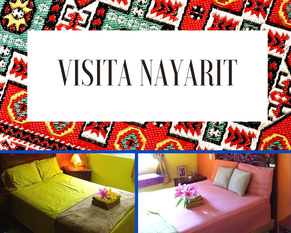 The image displays two separate sleeping areas, each featuring a bed with a distinct color scheme. One bed is covered with a bright yellow blanket and a decorative throw, while the other is dressed in a soft pink cover. A small decorative arrangement is placed on both beds.