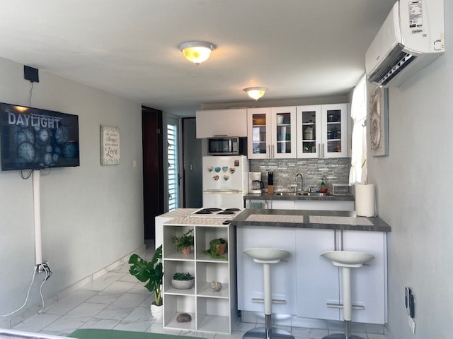 A modern kitchen area is featured, complete with a refrigerator, microwave, and stove. White cabinetry complements the gray countertops. Two barstools are positioned at the counter. A television mounted on the wall displays the word 'DAYLIGHT,' and natural light flows through a window.