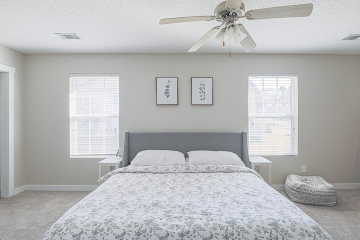 Chambre spacieuse avec literie moelleuse, lumière naturelle, ventilateur de plafond et lit king size pour un séjour confortable.