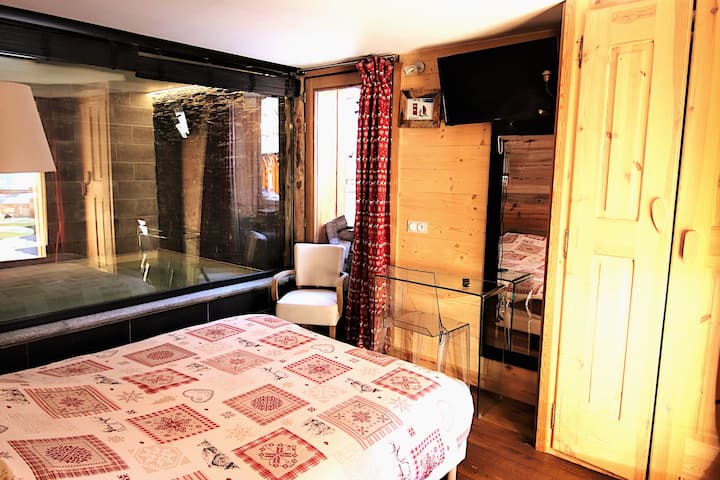 Chumba cha kulala 1 katika R0 kimewekewa vitanda 2 vya mtu mmoja ambavyo vinatengeneza kitanda 1 kikubwa wakati viko karibu. Inaangalia dimbwi la ndani upande wa kushoto. Ufikiaji wa jakuzi na sauna ya Kifini ni kupitia mlango wa glasi upande wa kulia.