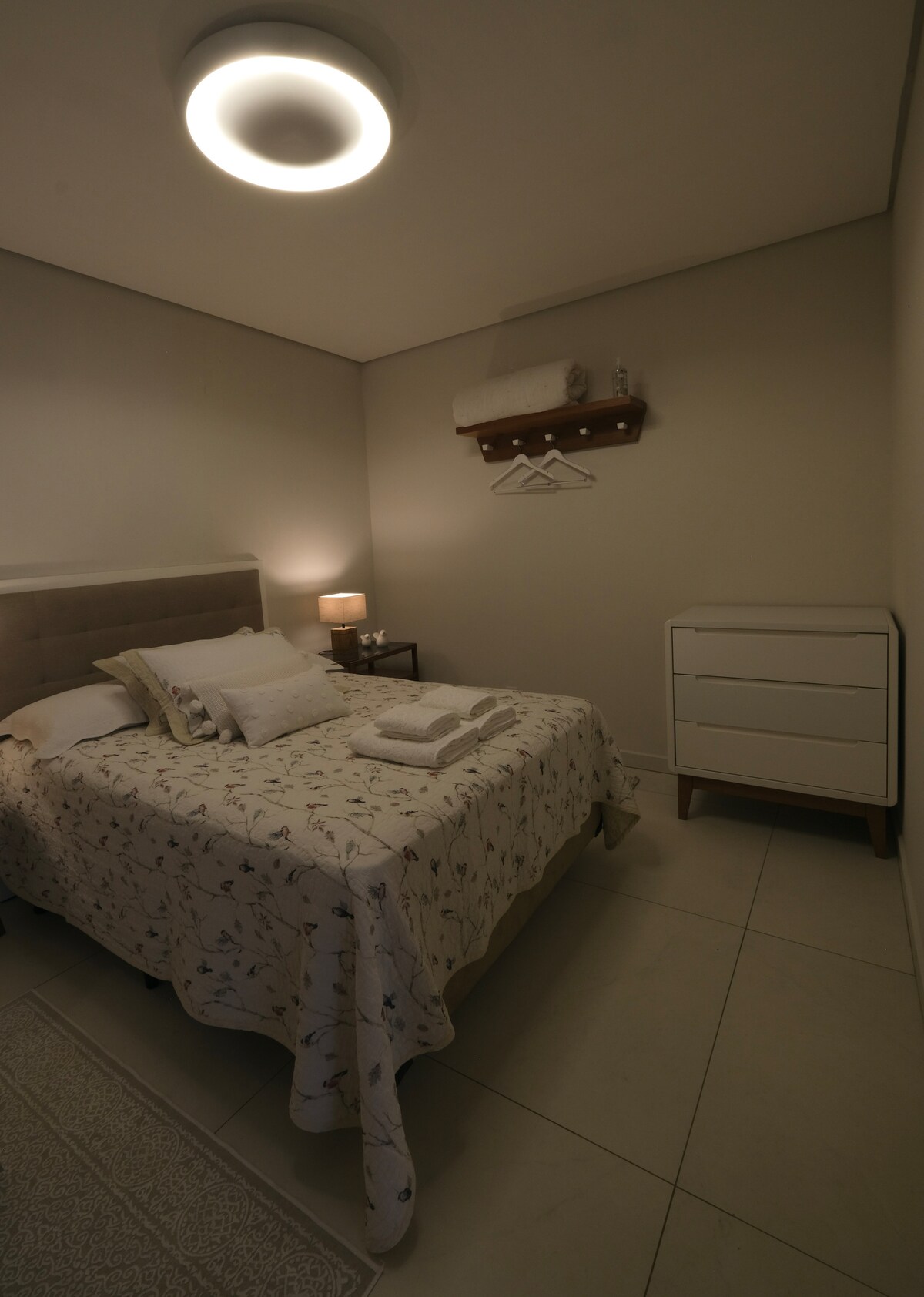 Spavaća soba s stalkom za odjeću i komodom s posteljinom i posteljinom za kupanje.