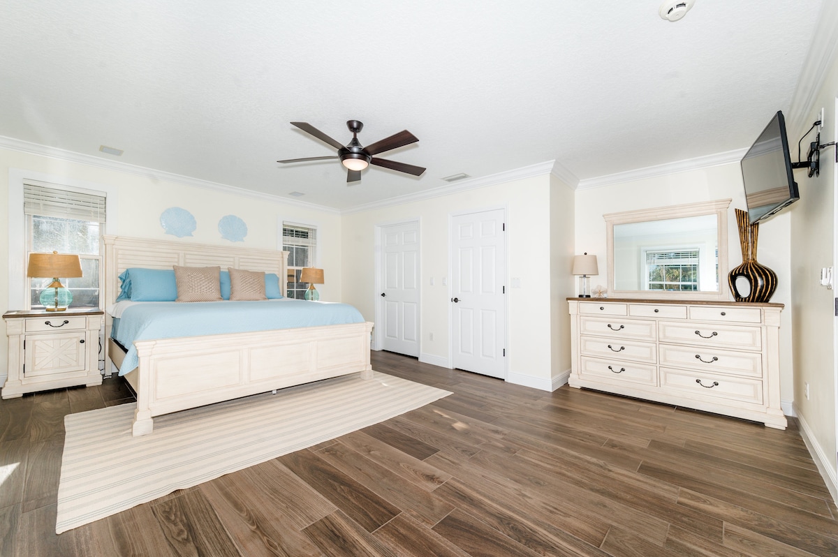 חדר שינה ראשי גדול עם מיטת קינג סייז, שידה, טלוויזיה עם מסך שטוח, נוף לים, ארון וחדר רחצה ראשי גדול. 