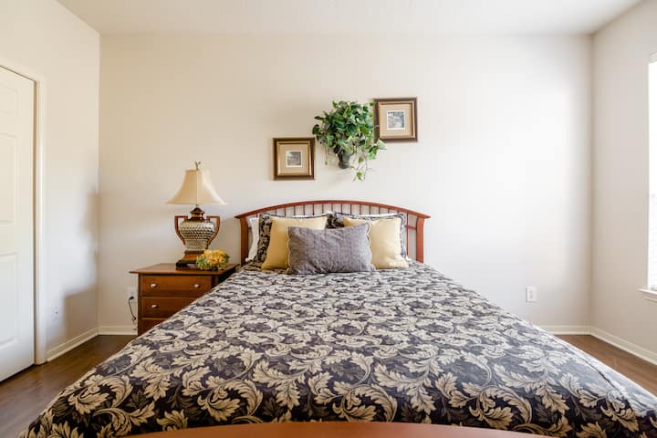 3er  dormitorio con cama tamaño queen, mesita de noche, alfombra, silla de cuero y otomana para que te relajes cerca de la ventana y una cama para niños pequeños que no se muestra en la imagen. Mucha luz natural. Armario para guardar tus pertenencias, 