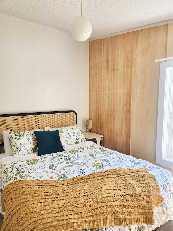 Una acogedora cama tamaño queen y un amplio armario, completo con edredón y mesita de noche, enchufes y ventilador para mantenerte cómodo.