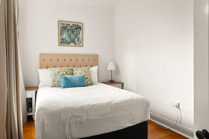 בחדר השינה השני שטוף שמש למעלה יש מיטה זוגית עם מצעים איכותיים ואחסון מלתחה.